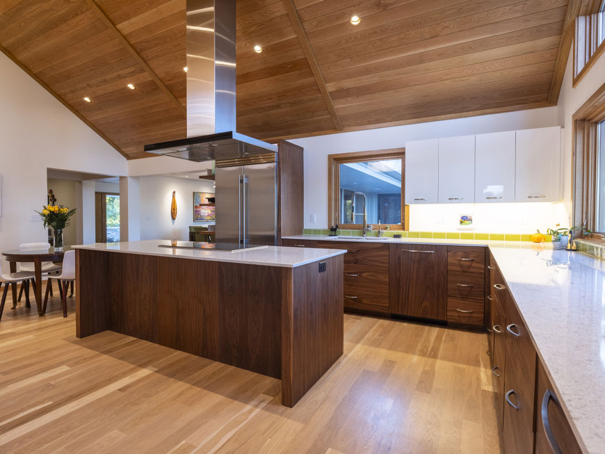 Modern kitchen redesign features a small kitchen table, cooktop island with stainless steel appliances.