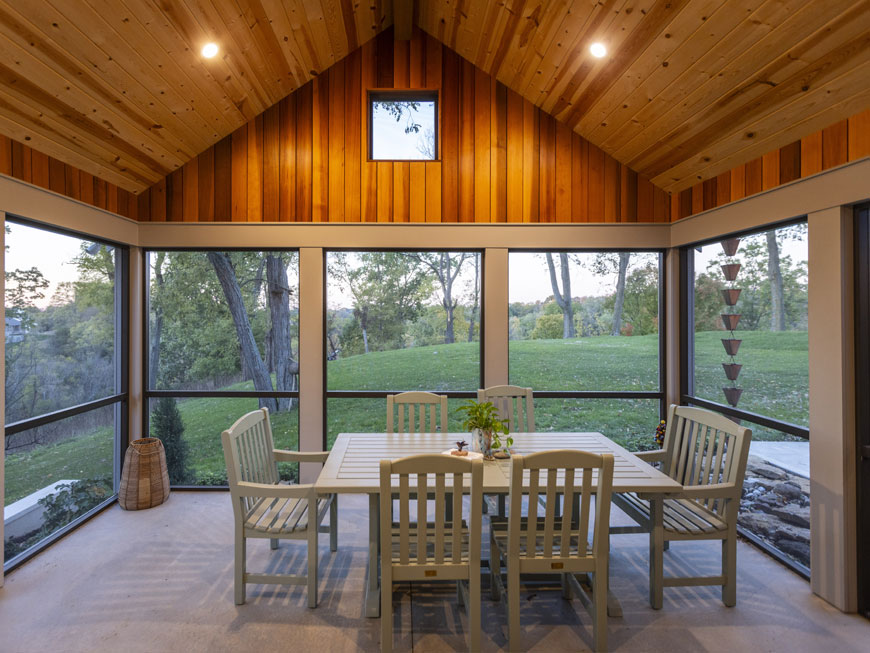 Modern screen porch addition added to mid-century modern home remodel by Kepes Architecture. Space features a wood-clad ceiling and large, floor-to-ceiling screen panels showing the nine acre property beyond.