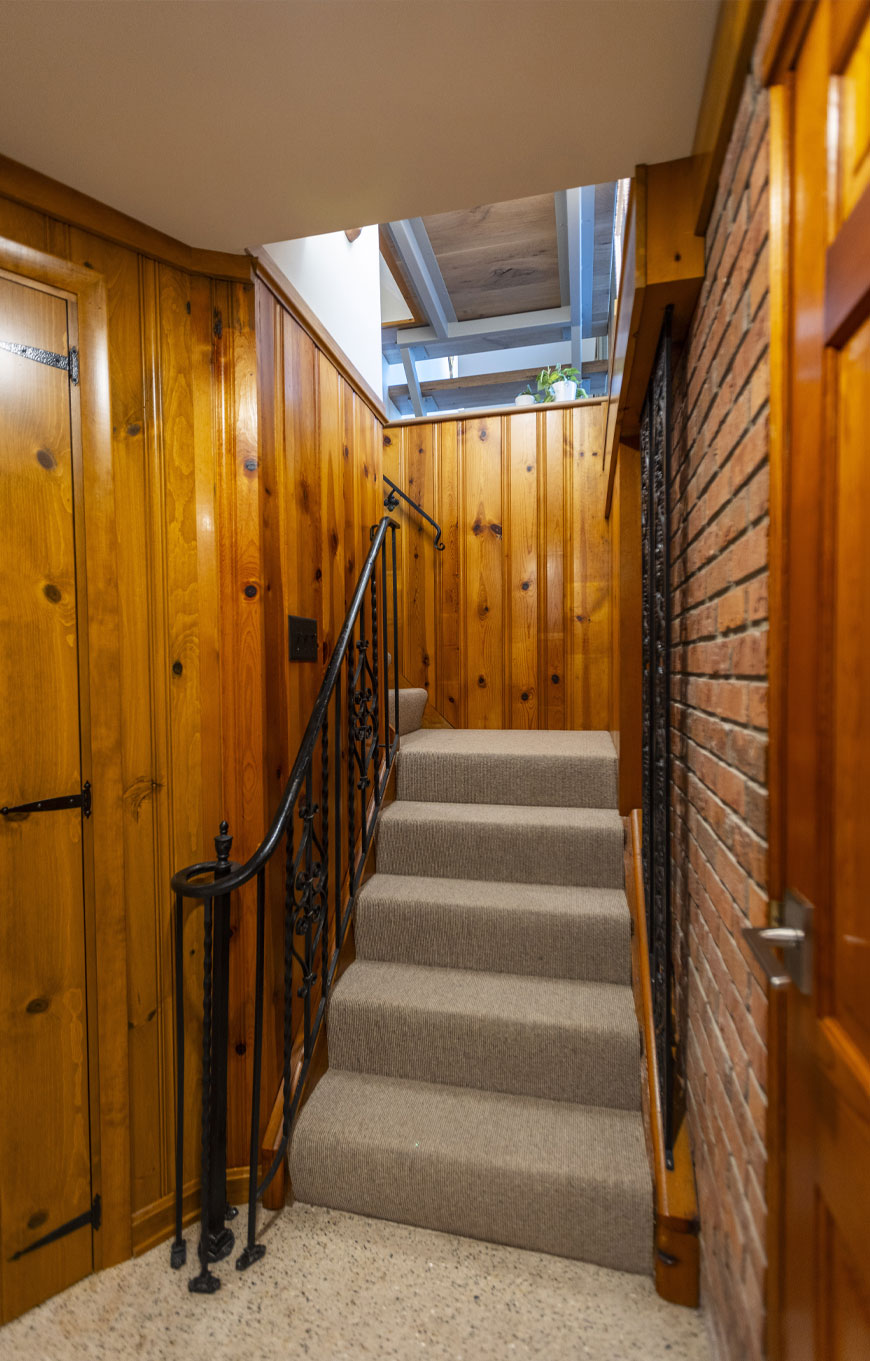 Restored pine paneled stairs lead to lower level rec room.