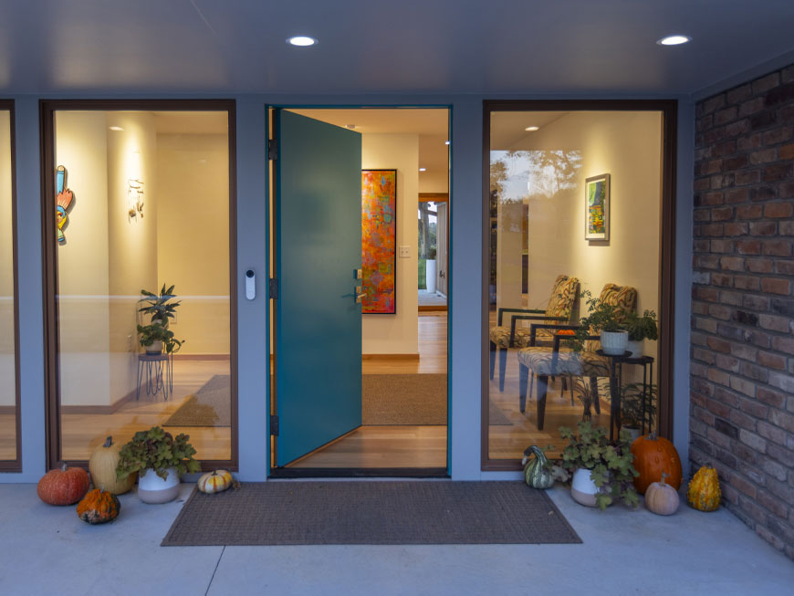 Entrance door of home with art hung on white walls. Remodel done by Chris Kepes.